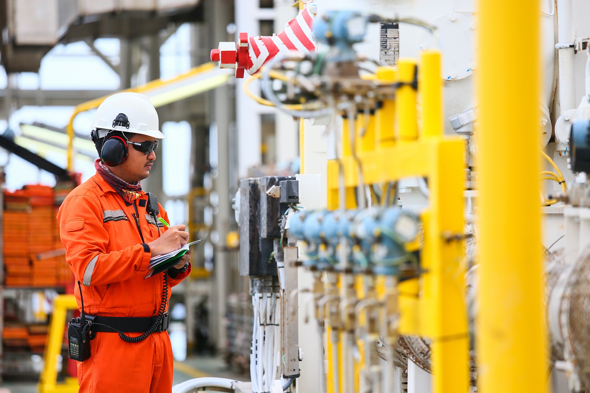 Operator recording operation of oil and gas process at oil and rig plant.